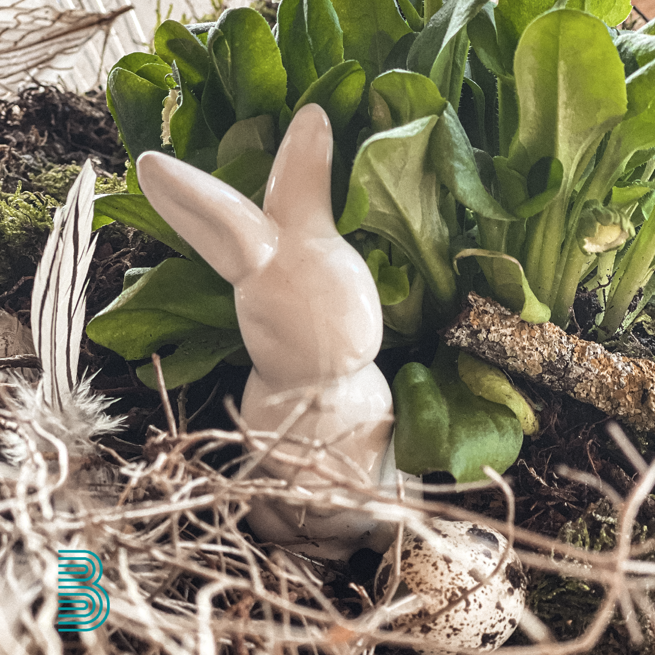 Eine DEkoosterhase steht inmitten österlichem Gesteck.