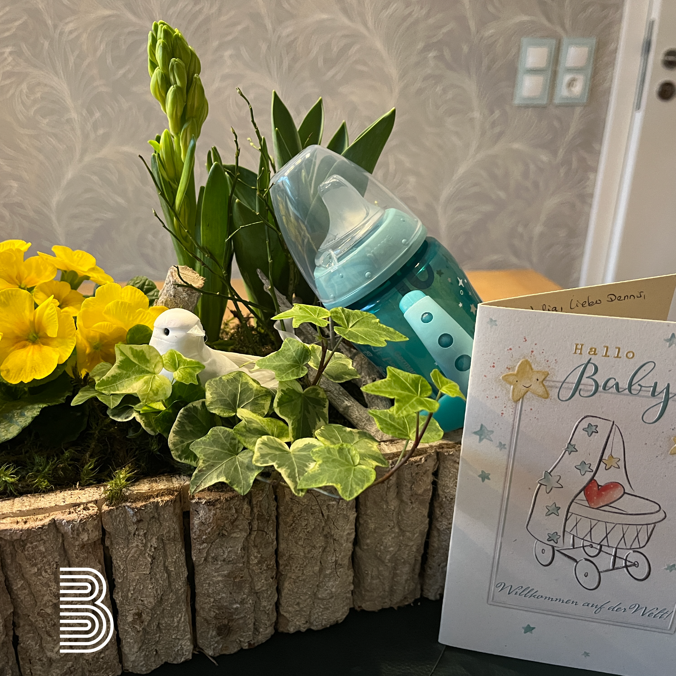 Baby-Geschenk mit Flasche und Blumen.