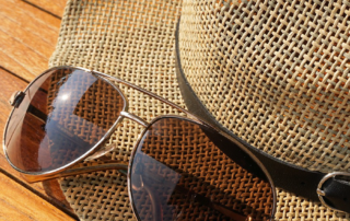 Sonnebrille liegt auf Sommerhut.