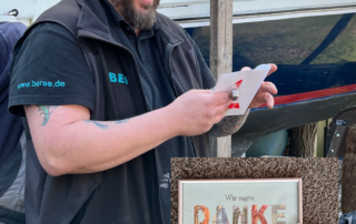 Dennis Burkert packt ein Geschenk aus und lacht.
