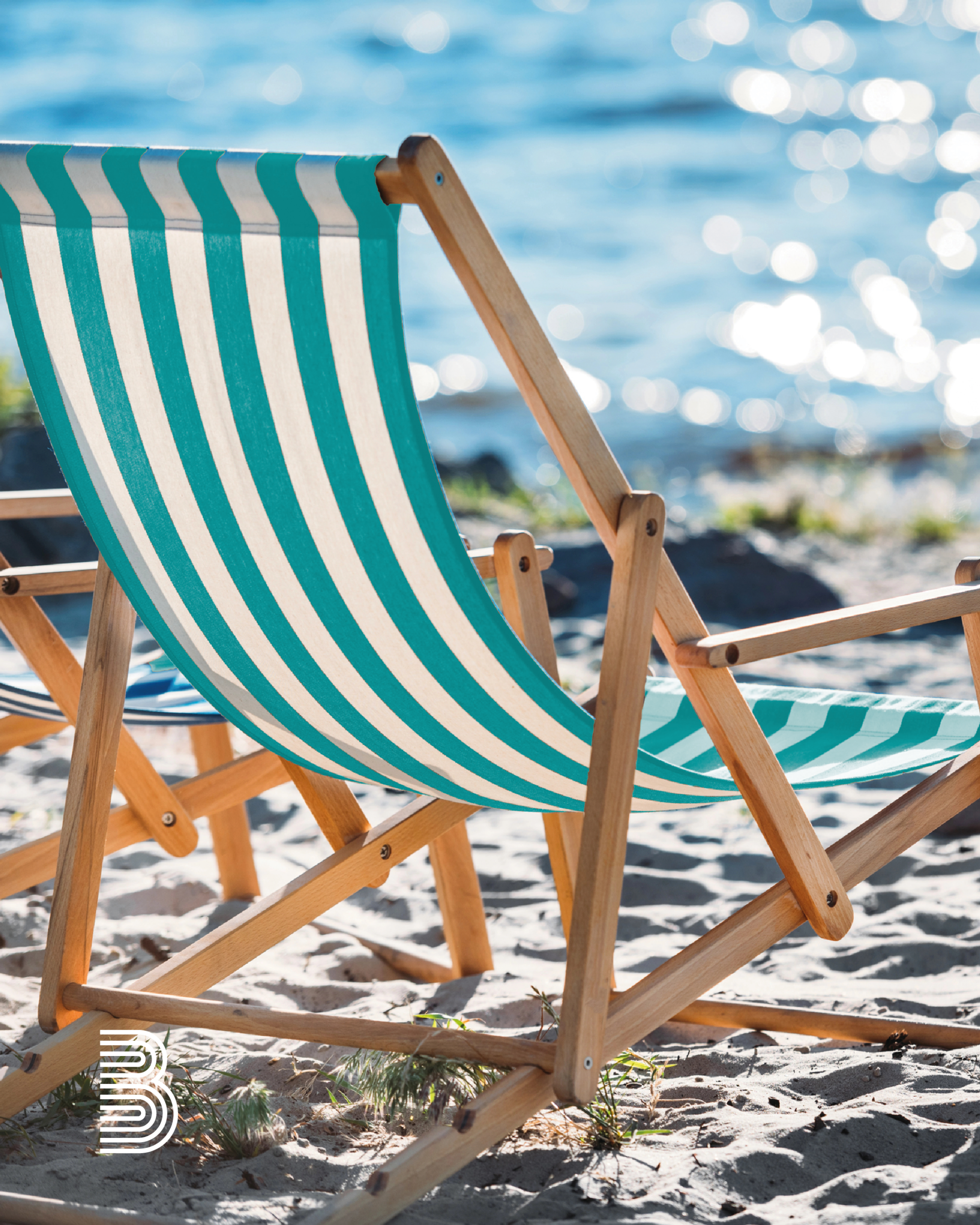 Ein Liegestuhl steht im Sand am Meer.