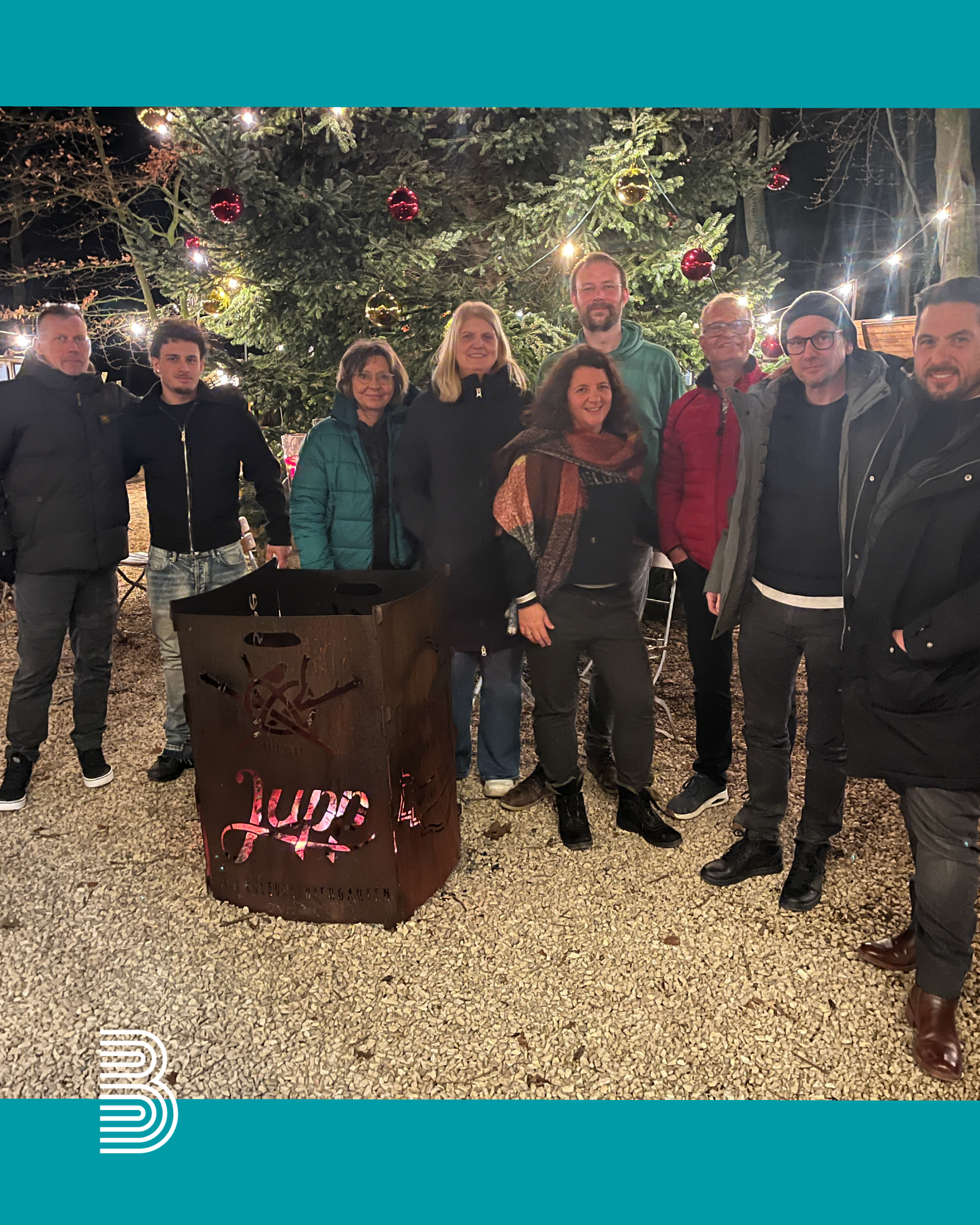 Menschen stehen um eine Feuertonne und lachen in die Kamera.