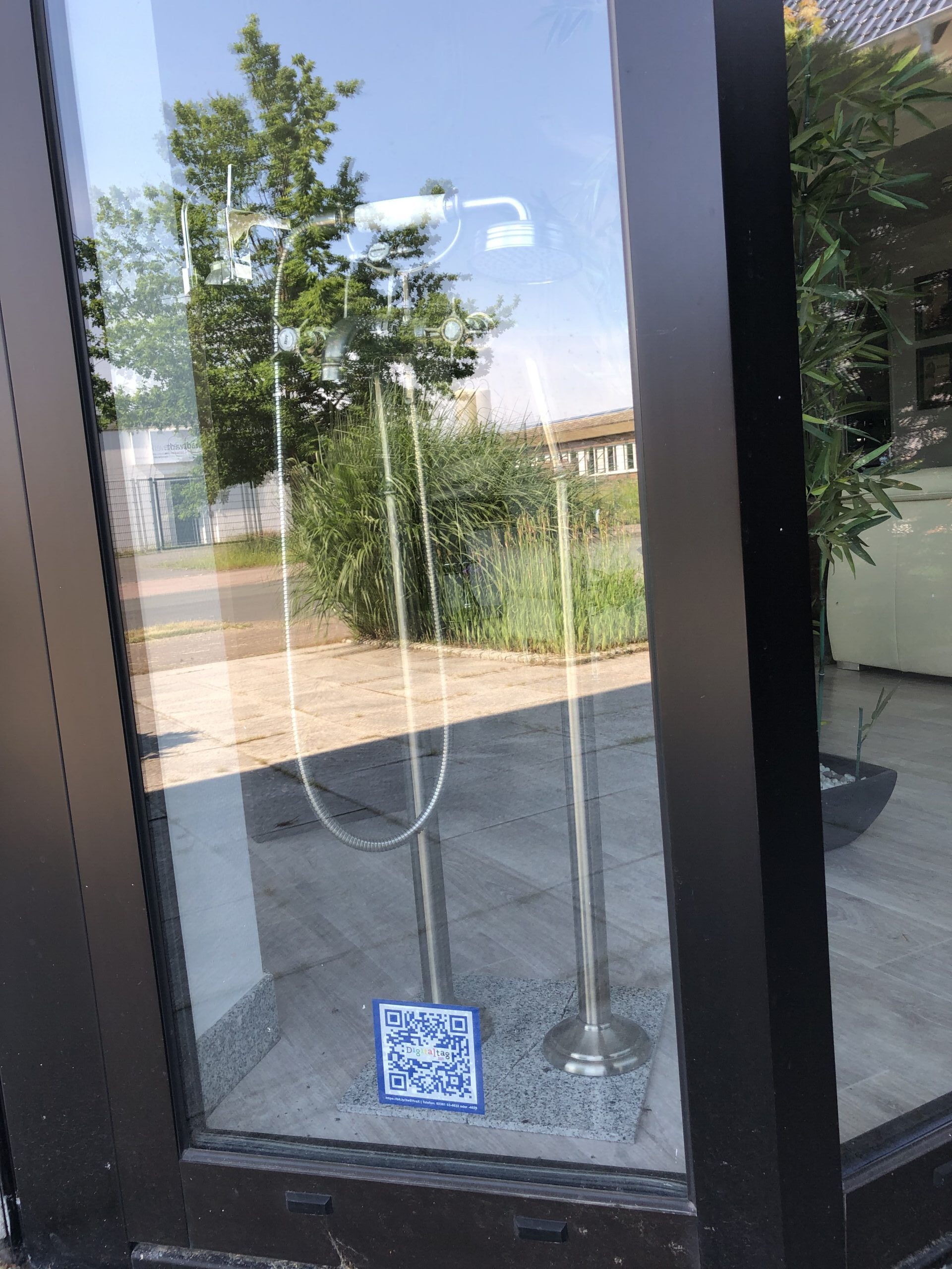 Ein QR-Code klebt an einer gläsernen Eingangstür.