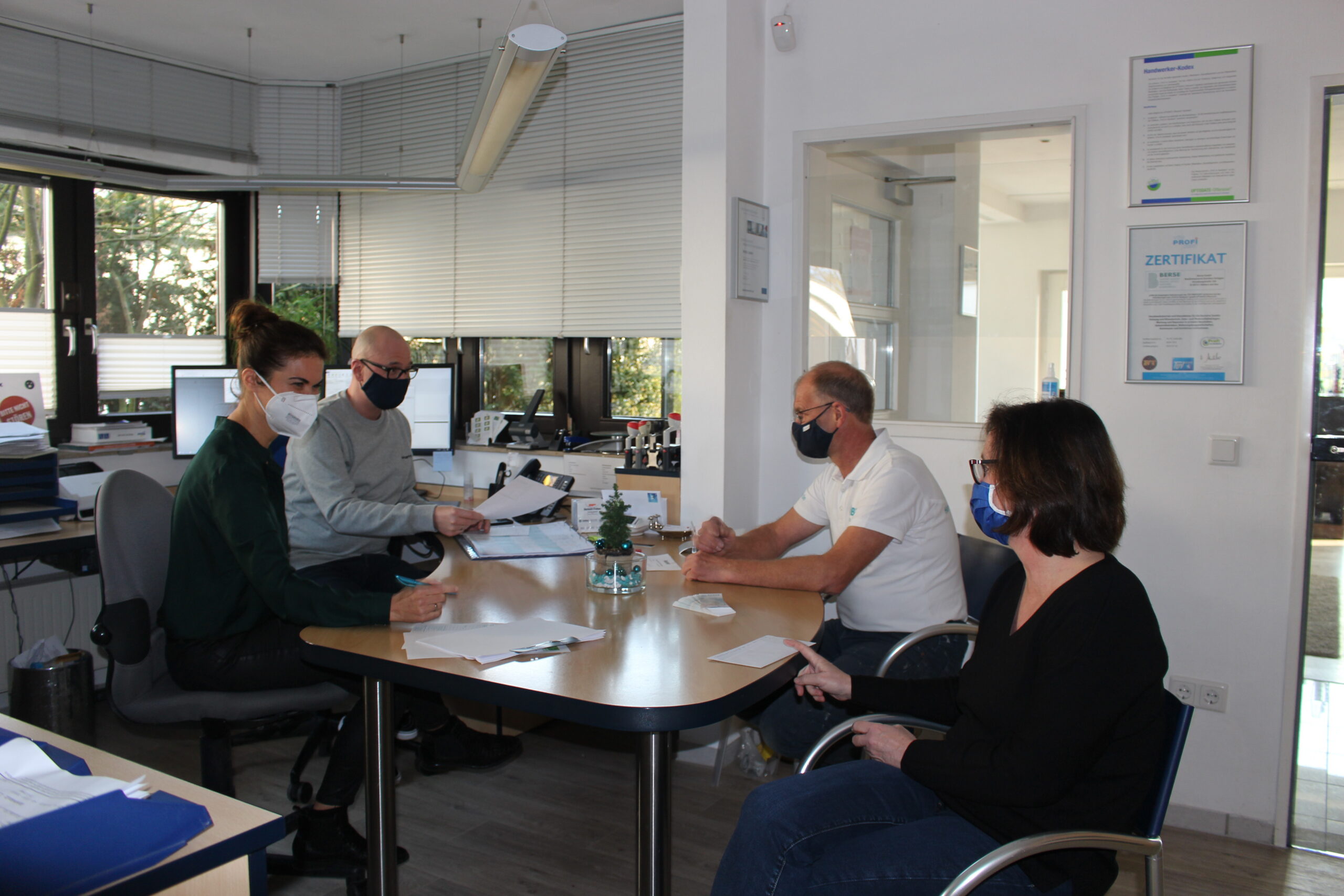 Coaching-Situation in der Firma Berse. Menschen sitzen gemeinsam an einem Tisch.