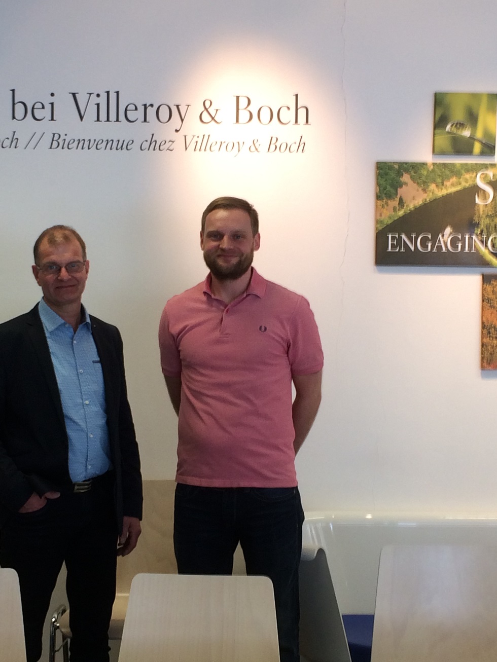 Ulrich Berse mit Daniel Goorkotte (Firma Elting) beim Firmenbesuch von Villeroy & Boch vor einem Logo von Villeroy & Boch.