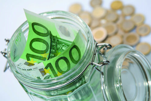 Zwei Hundert-Euro-Scheine stecken in einem Einmachglas. Dahinter liegt Münzgeld.