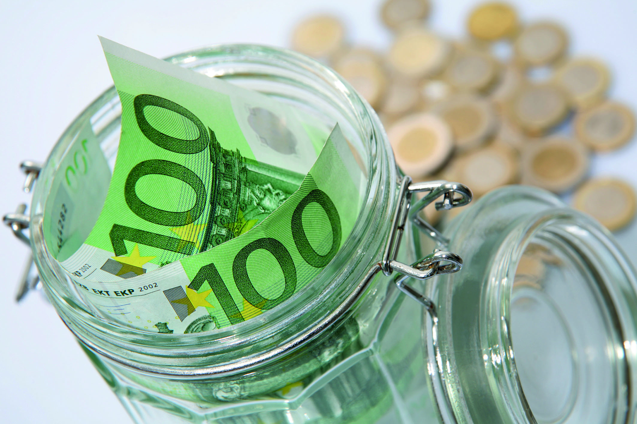 Zwei Hundert-Euro-Scheine stecken in einem Einmachglas. Dahinter liegt Münzgeld.