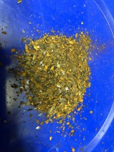 Rost aus einem Heizkörper liegt in einem blauen Eimer.