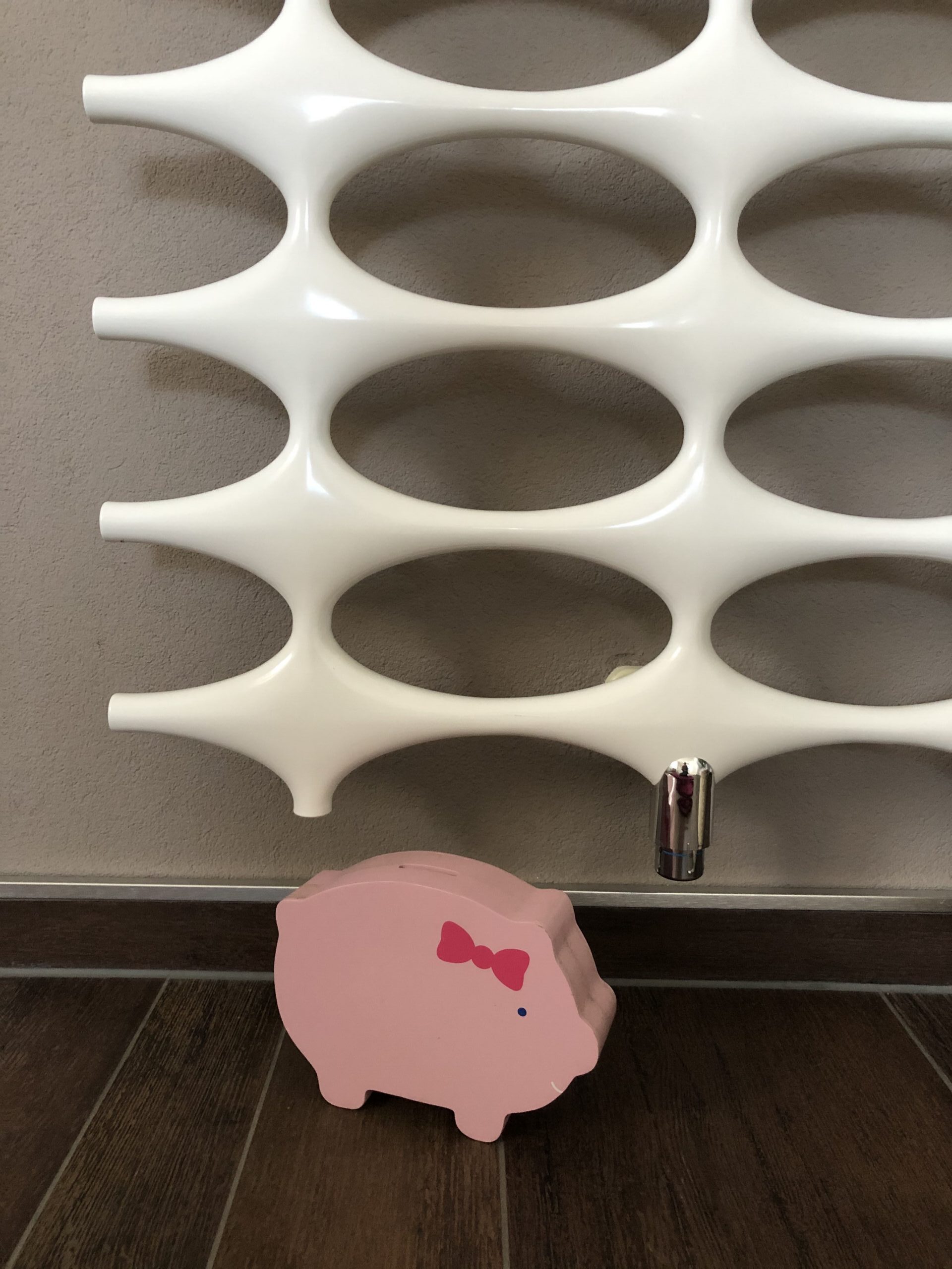 Ein Sparschwein steht unter einem Heizkörper.
