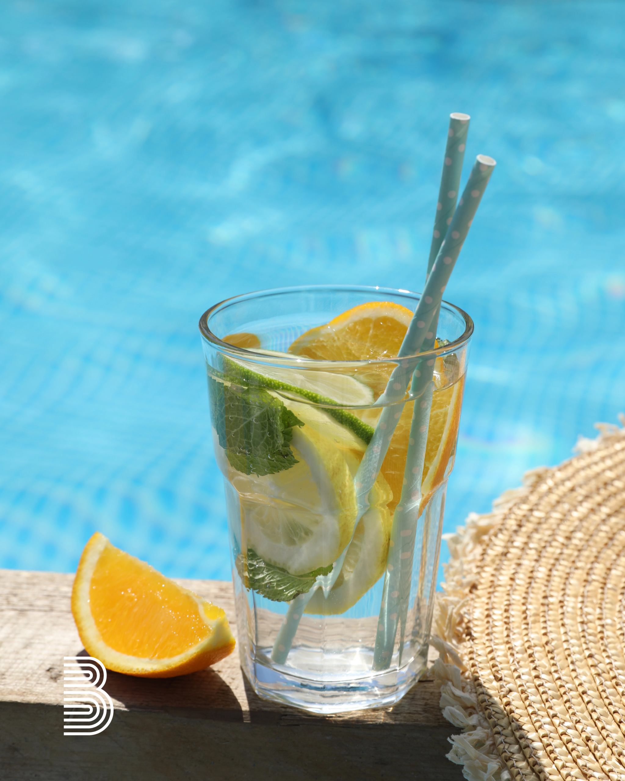 Getränk mit Früchten und Strohhalm am Pool.